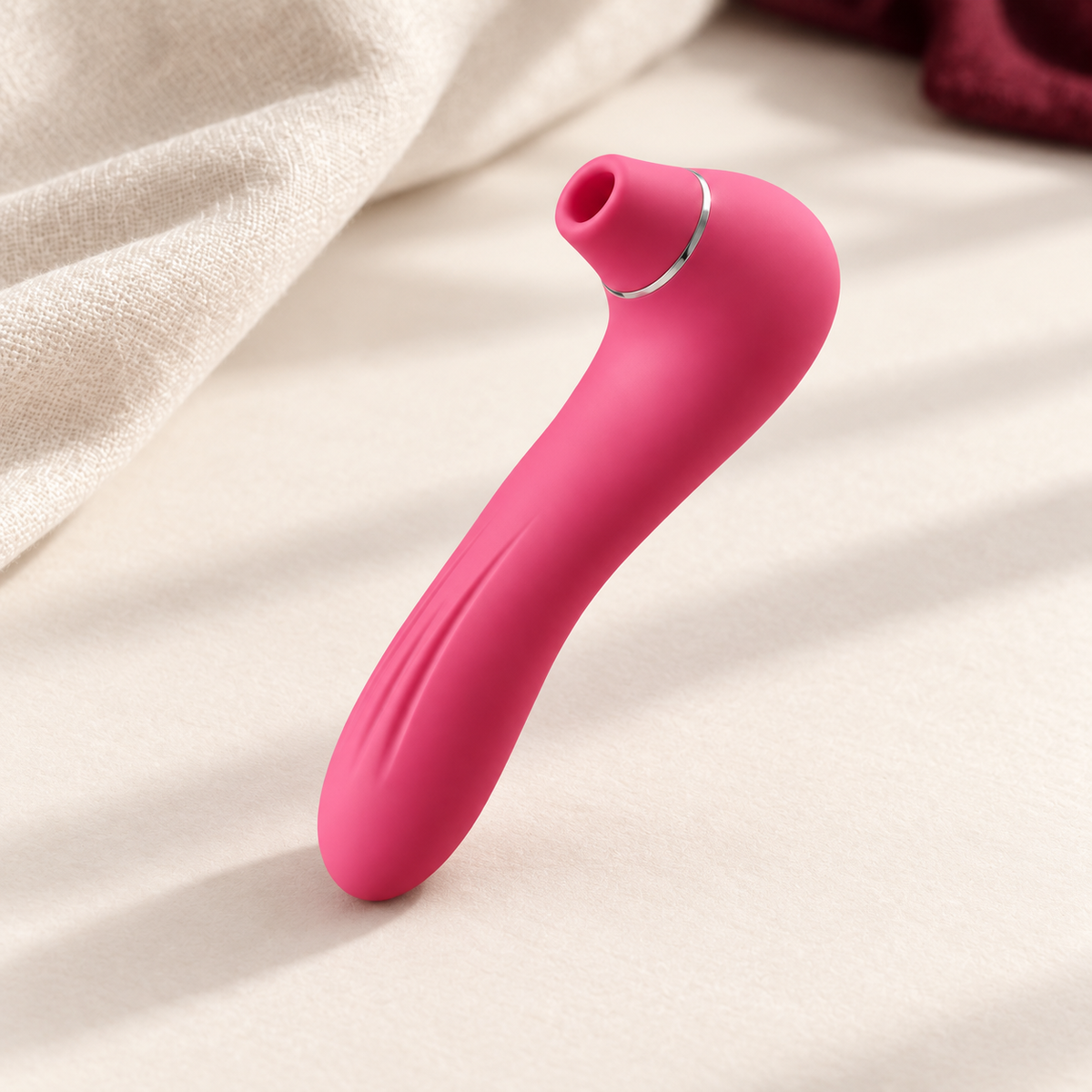 NOLEVA Impuls-Massager in Pink mit silbernem Ring auf heller textiler Unterlage.